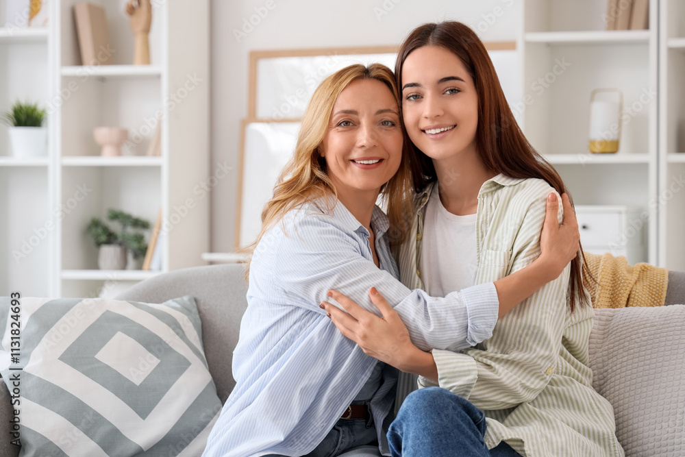 Obraz premium Young woman hugging her mother while sitting on sofa at home. International Hug Day