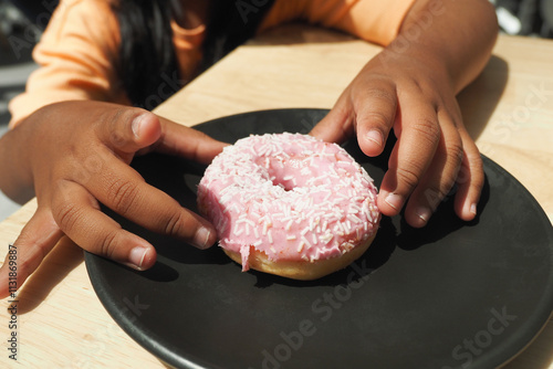 a kid hand pick a chocolate donut photo