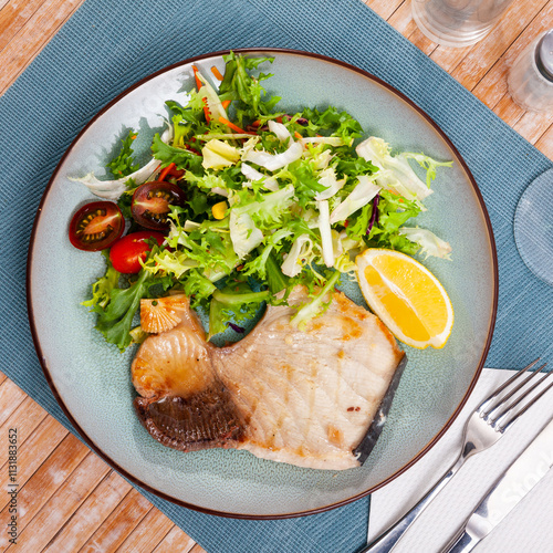 Appetizing baked steak of porbeagle with fresh greens salad with cherry tomatoes and lemon. photo