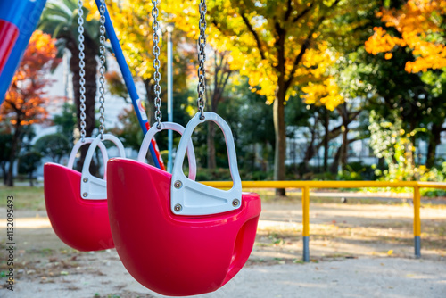 Red swing on playground in colorful authumn public park. photo