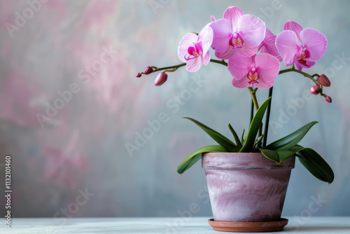 Artificial orchid plant in flower pot on white marble table. Space for text