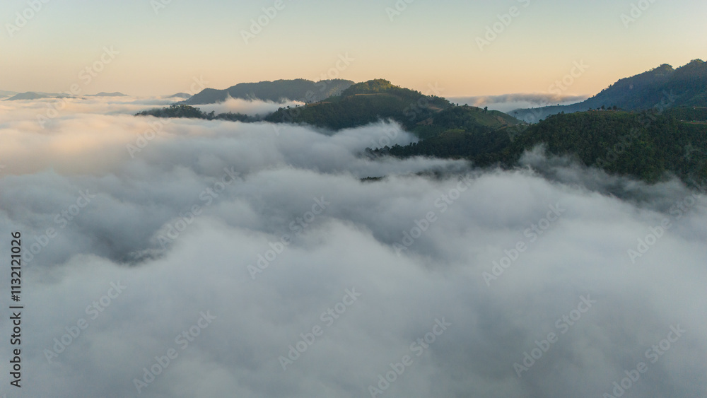 Obraz premium aerial overview of a sea of clouds glowing in golden hues during sunrise over hills