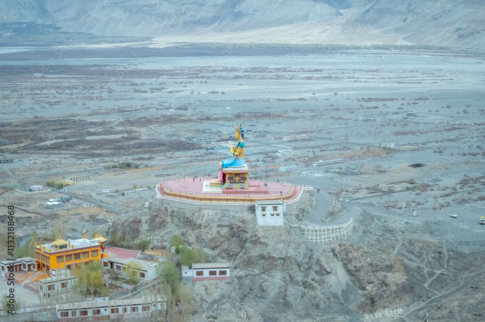 Obraz premium The Maitreya Buddha statue with Nubra Valley in the background from Diskit Monastery or Diskit Gompa, Nubra valley, Leh Ladakh