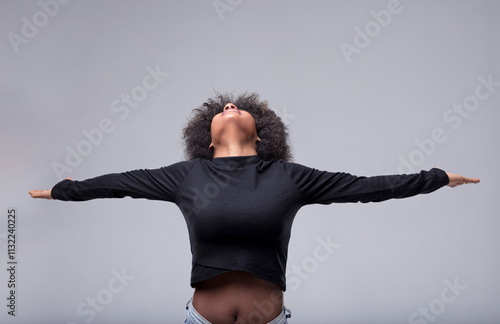 Young woman opening arms and looking up with hope