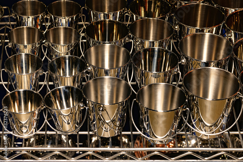 Unique collection of polished metal cups arranged on a silver rack in a vibrant setting