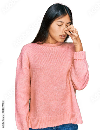 Beautiful young asian woman wearing casual winter sweater smelling something stinky and disgusting, intolerable smell, holding breath with fingers on nose. bad smell