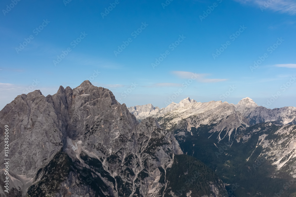 Fototapeta premium Hiking trail with scenic view of rugged mountain peak Jalovec in wild Julian Alps seen from Triglav National Park, Vrsic pass, Slovenia. Wanderlust Slovenian Alps. Sharp steep ridges in alpine terrain