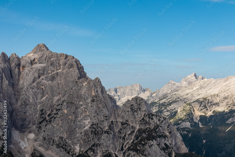 Obraz premium Hiking trail with scenic view of rugged mountain peak Jalovec in wild Julian Alps seen from Triglav National Park, Vrsic pass, Slovenia. Wanderlust Slovenian Alps. Sharp steep ridges in alpine terrain