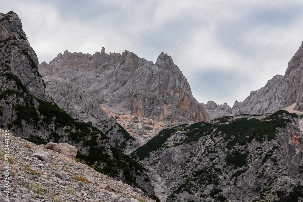 Fototapeta premium Hiking trail with scenic view of rugged majestic mountain peaks of Julian Alps seen from Krnica valley, Vrsic pass, Slovenia. Wanderlust wild Slovenian Alps. Ridges with sharp edges and steep cliffs