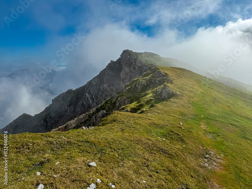 Hiking trail over alpine pasture towards cloud covered mountain peak Begunjscica, Loibl Pass, Karawanks, Slovenia Austria. Wanderlust Slovenian Alps in summer. Peace, tranquility in alpine wilderness photo