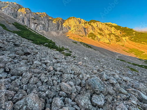 Mountain peak Begunjscica bathed in warm sunrise light seen from Loibl Pass in Karawanks, border Slovenia Austria. Wanderlust in Austrian Slovenian Alps. Tranquil atmosphere in alpine wilderness. Hike photo