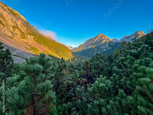 Mountain peak Wertatscha bathed in warm sunrise light seen from Loibl Pass in Karawanks, border Slovenia Austria. Wanderlust in Austrian Slovenian Alps. Tranquil atmosphere in alpine wilderness. Hike photo