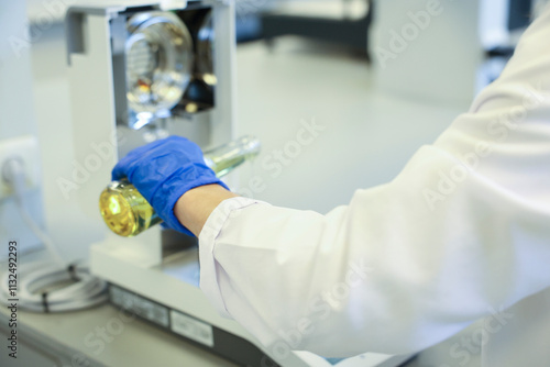 Scientist in laboratory pouring liquid sample into high-tech equipment for chemical analysis. Professional lab setting for quality control, testing, and scientific research in modern industries