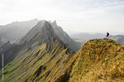 Man taking a smartphone photo of rocky mountains in Appenzell Alps at sunset. Eco tourism in Switzerland