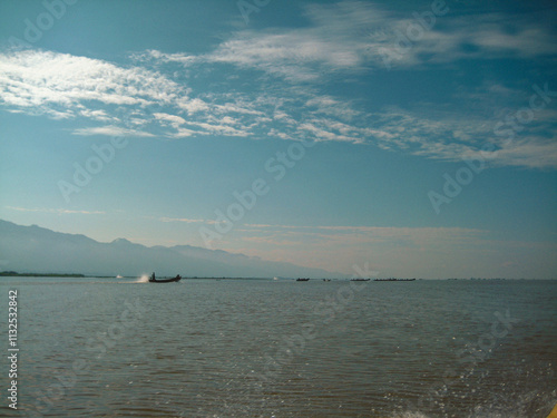  Inle Boat Station in Inle Nyaung Shwe Canal. A series of fishing boats along the river generated by Inle Lake. Homes and Pagoda temple in the background.Daily life in Inlay town, boat station to visi