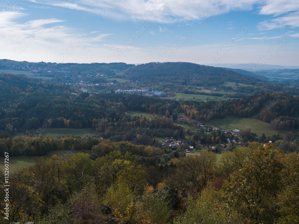 Panoramic view from viewpoint Stredni vrch near Dolni Prysk, Ceska Kamenice. Autumn landscape with colorful forest, hills and blue cloudy sky in Luzicke hory Lusatian Mountains, Czech Republic. Panoramic view from viewpoint Stredni vrch near Dolni Prysk, Ceska Kamenice. Autumn landscape with colorful forest, hills and blue cloudy sky in Luzicke hory Lusatian Mountains, Czech Republic.