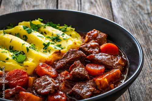 Irish stew for St. Patrick's Day - roast beef in beer with vegetables served with mashed potatoes on wooden table