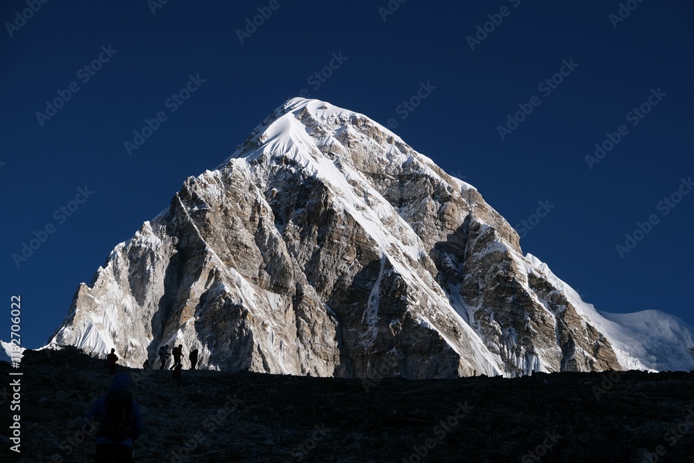 Kala Patthar mount with hiking silhouettes of people and Pumori mount in background. Kala Patthar is the best viewpoint of Mount Everest. Himalayas, Sagarmatha National Park, Nepal.