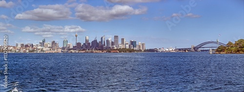 Sydney skyline featuring the Harbour Bridge, Opera House, and Sydney Tower viewed from the water under a clear sky photo