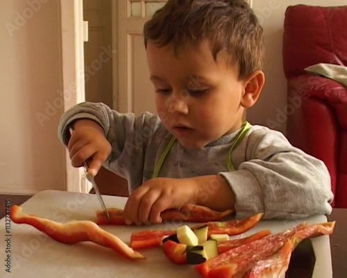 Vintage camcorder shot of a child cooking and cutting a vegetable, 90's, VHS, France
