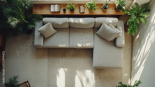 A minimalist hotel living room, top view of a neutral gray sectional sofa, a slim wooden shelf adorned with small potted plants and a few books, set on a light beige rug,