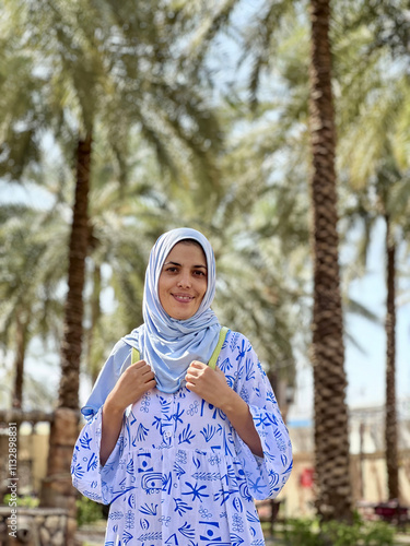 Portrait of a young Arab girl in a blue hijab and blue dress in the paradise date garden. The date garden of Caliph Usman in Medina.