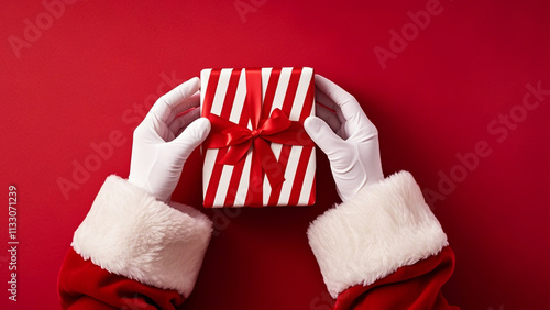 Santa Claus hands holding a beautifully wrapped present with a red and white striped ribbon PNG....