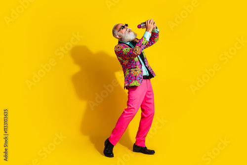 Full length portrait of charismatic nice man sing wear pink pants colorful blazer isolated on yellow background photo