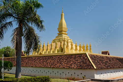 The scenery of Pha That Luang pagoda in Vientiane, the capital of Laos with the palm tree outside the wall.