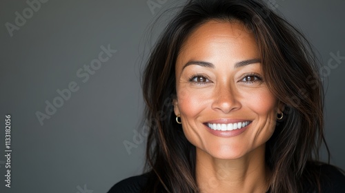 A portrait of a confident woman smiling with luminous eyes, her long brown hair flows, set against a soft-focus background, exuding elegance and warmth.