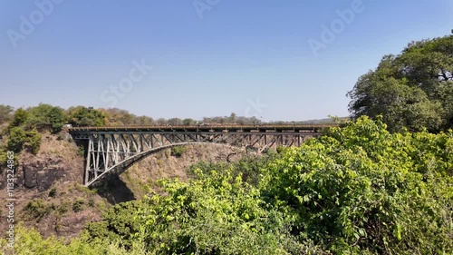 Bridge Border At Victoria Falls Matabeleland North Zimbabwe. Iconic Structure Of Bridge Connecting Landmarks Streets. Idyllic Forest Powerful Waterfall Stunning. Powerful Waterfall Travel Landscape. photo