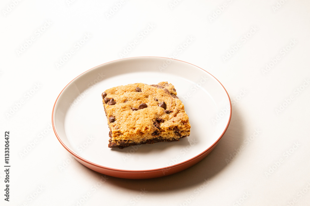 Chocolate Chip Cookie Bar on White Plate with Red Rim on white background Chocolate Chip Cookie Bar on White Plate with Red Rim on white background