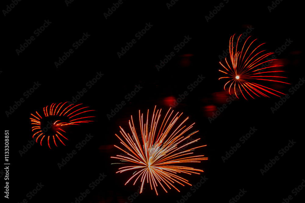 Fototapeta premium Red-orange sparks of fireworks on the black sky. .