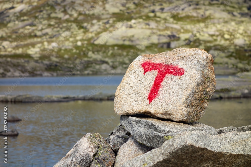 Navigation stone on trail to Trolltunga, Norway in front of lake