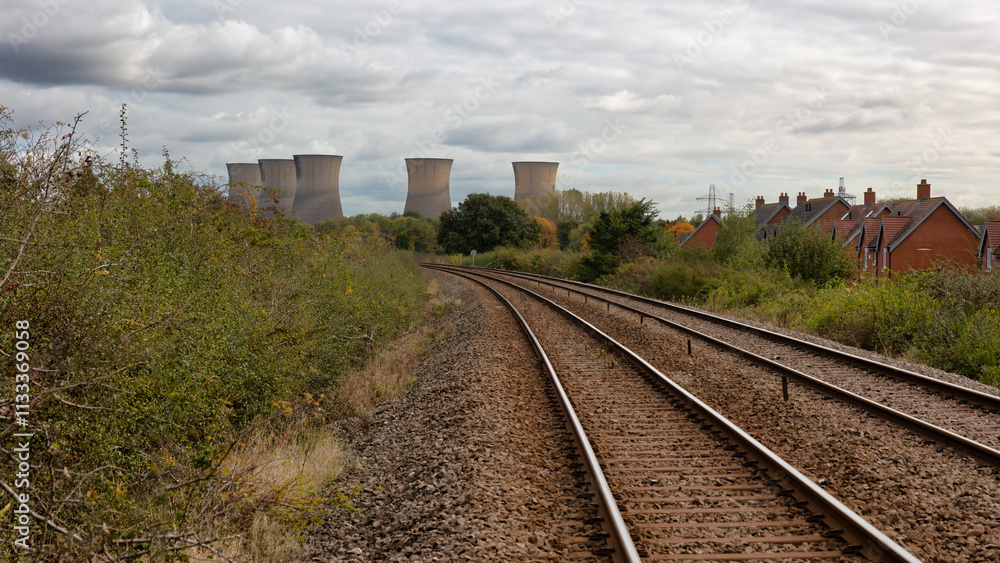 Obraz premium a railway track leads the viewer to five cooling towers at a power station in the distance. Located in Willington, Derbyshire