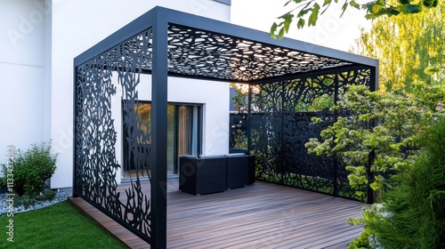 Modern black metal pergola with laser-cut design, shading patio furniture on a wooden deck.
