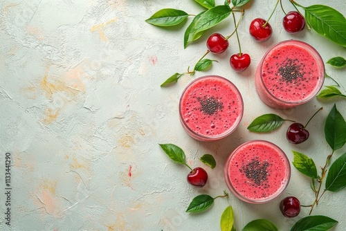 Refreshing cherry smoothies with seeds and green leaves on a light background