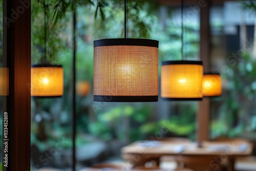 Warmly lit hanging lanterns illuminate serene outdoor dining area surrounded ...