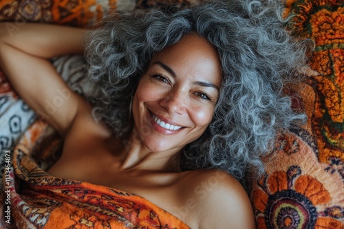 Smiling woman resting on colorful blanket in cozy setting at sunset