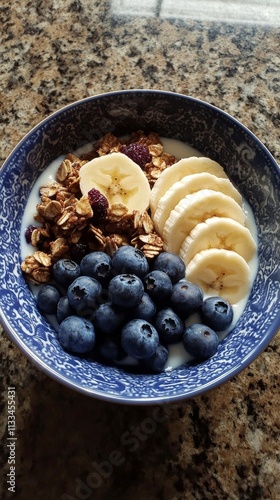 Delicious bowl of yogurt topped with fresh fruit and granola served on a kitc...