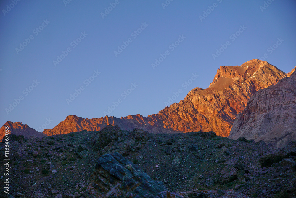 Fototapeta premium Sunset in the mountains. The setting sun highlights the mountain peaks with orange light