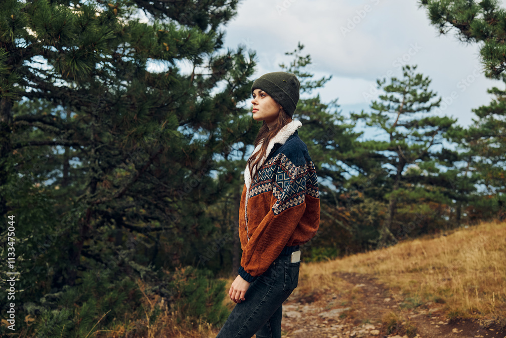 Naklejka premium A young woman exploring the tranquil beauty of nature on a forest trail in stylish attire