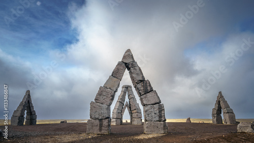 Two hikers in red jackets stand near the Arctic Henge, a stone monument resembling Stonehenge in Iceland. photo