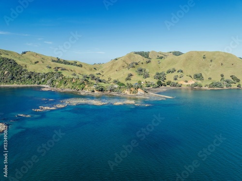 Coastal New Zealand landscape. Tranquil bay with grassy hills and small buildings. Aerial view. , PORT CHARLES, COROMANDEL PENINSULA, NEW ZEALAND photo