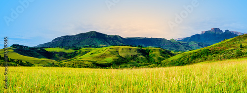 Rolling hills and lush valley grassland with Cathkin Peak of Drakensberg mountain, panorama shot, KwaZulu-Natal, South Africa photo