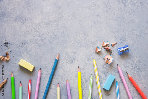 Pencil sharpener, erasers and pencils on a grey background.