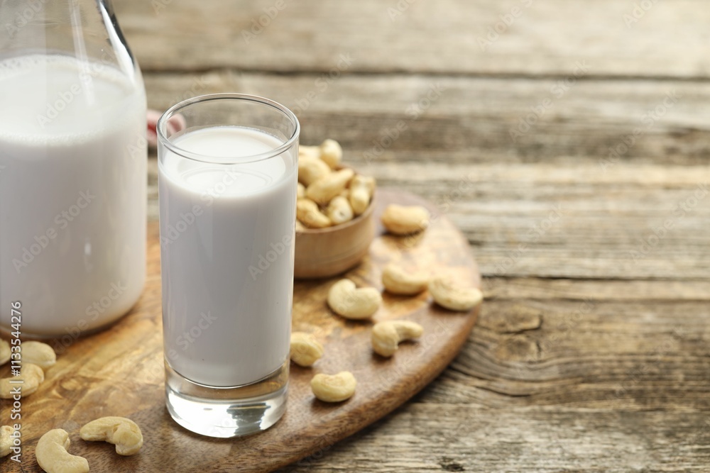 Fresh cashew milk in glass, bottle and nuts on wooden table, closeup. Space for text Fresh cashew milk in glass, bottle and nuts on wooden table, closeup. Space for text