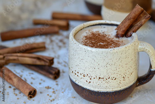 rich cinnamon latte in handcrafted ceramic mug, weathered oak surface photo