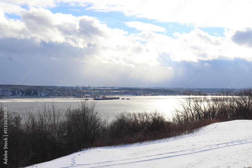 Winter landscape in a park in Quebec city with trees a sunny sky and a large river. Winter and december calendar. A background with snow and an horizon. The St-Laurent river in winter. Winter landscape in a park in Quebec city with trees a sunny sky and a large river. Winter and december calendar. A background with snow and an horizon. The St-Laurent river in winter.