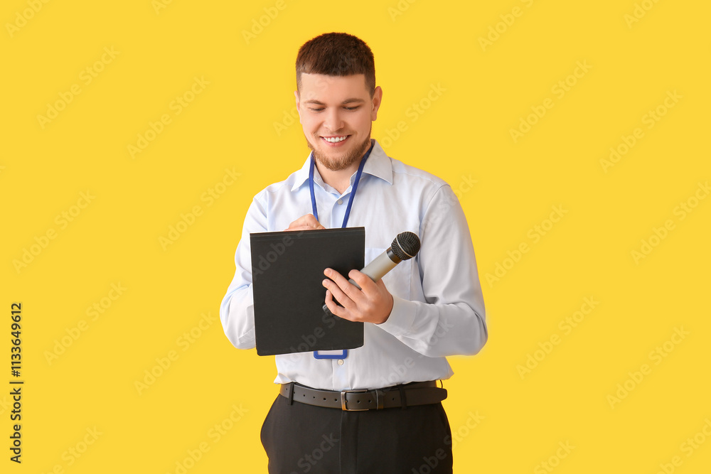 Male reporter with microphone writing something on clipboard against yellow background Male reporter with microphone writing something on clipboard against yellow background